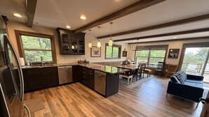 A modern kitchen with wooden flooring, built-in appliances, and a dining area with a view. - Skye High Hideaway SLEEPS 18, 7 BRs, 4 baths, 2 living areas, a pool table, private hot tub, fire pit, and beach passes. (Lake Harmony)