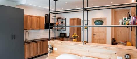 A modern bedroom with a wooden headboard, a bed with white bedding, a bedside table, and a small bedside lamp.