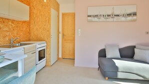 A compact kitchen with a built-in oven, a sink, and a wooden wall.
