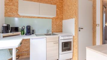 Una cucina compatta con forno a microonde, macchina del caffè e piccolo frigorifero.