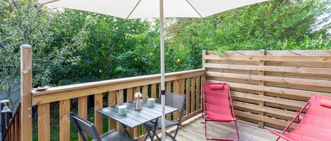 An outdoor deck with a table and chairs, a wooden fence, and a large umbrella.