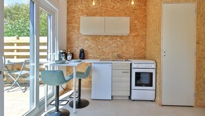 A compact kitchen with a built-in oven, a refrigerator, and a sink. There is a dining area with a table and chairs.