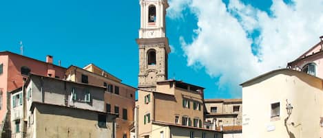 Un pueblo histórico con una destacada torre del reloj, un puente de piedra y arquitectura tradicional.