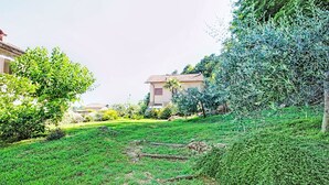 Un quartier résidentiel avec une pelouse verdoyante, un chemin et un bâtiment doté d’un toit en tuiles.