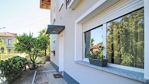 Un bâtiment moderne doté d’un balcon, d’un petit jardin et d’une fenêtre ornée d’une plante.
