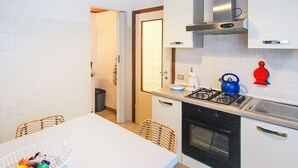 Une cuisine compacte avec des meubles blancs, une cuisinière à gaz et une hotte en acier inoxydable.