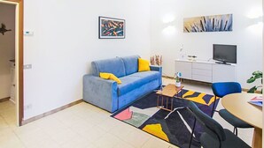 Un salon moderne avec un canapé bleu, une petite table basse et un coin repas comprenant une table et des chaises.