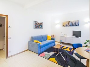Un salon moderne avec un canapé bleu, une petite table basse et un coin repas comprenant une table et des chaises.
