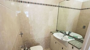 Et badeværelse med toilet, håndvask og brusebad.