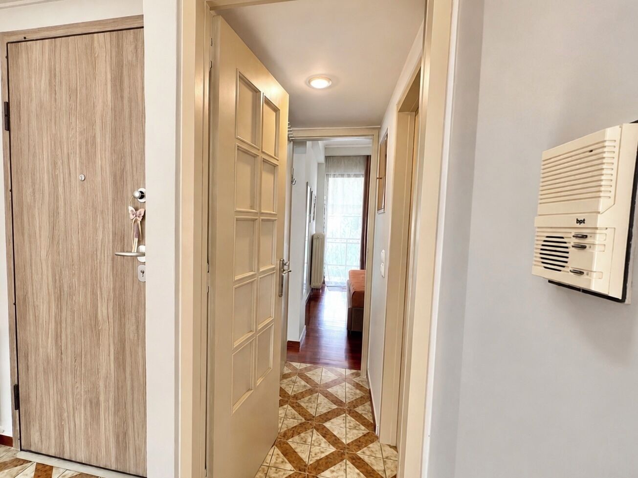 A hallway with a wooden door, a radiator, and a tiled floor.