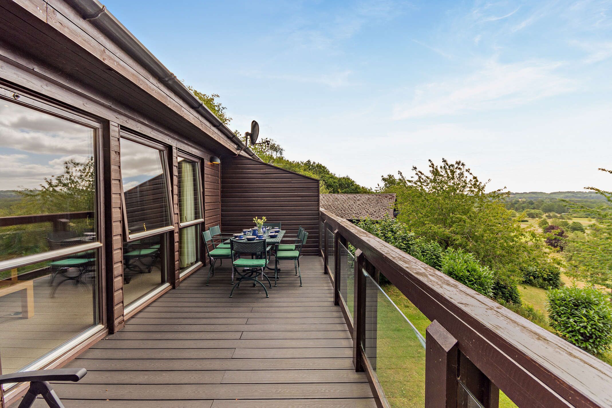A wooden deck with a table and chairs, overlooking a landscape.