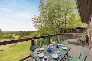 Eine Terrassensitzgruppe im Freien mit Tisch, gedeckt für ein Essen, umgeben von Grün und Blick auf die Landschaft.