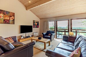 A living room with a flat-screen TV, a coffee table, leather sofas, and artwork on the walls.