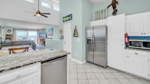 A modern kitchen with a large island, stainless steel appliances, and a view to the outside. - Peaceful Pearl (North Topsail Beach)