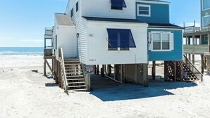 A multi-level beach house with a staircase leading to the main entrance, a small porch, and a view of the ocean. - Peaceful Pearl (North Topsail Beach)