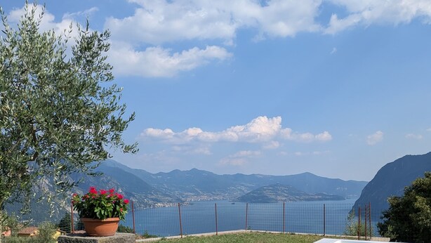 A pool area with a view of the sea and mountains, surrounded by pebbles and plants. - Corte Furmignano 🏡 A farmhouse surrounded by greenery with a spectacular view of the lake (Esmate)