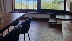 A room with a large window, a wooden ceiling, and a tiled floor. - Corte Furmignano 🏡 A farmhouse surrounded by greenery with a spectacular view of the lake (Esmate)