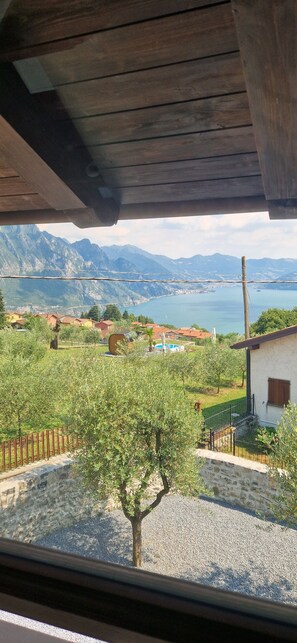 Blick aus einem Gebäude auf eine gebirgige Landschaft mit See und Häusern.