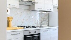 A modern kitchen with white cabinets, a marble backsplash, a gas stove, and a built-in oven. - Monteverde Marí House Vacation Home with Wi-Fi (Rome)