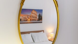 A bed with white linens, a nightstand with a lamp, and a framed picture of the Colosseum on the wall. - Monteverde Marí House Vacation Home with Wi-Fi (Rome)