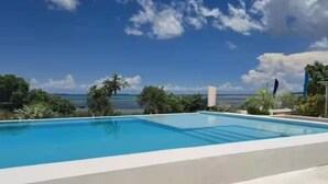 Piscina rectangular con cielo azul despejado y paisaje lejano.