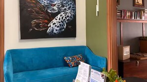 Una habitación con un sofá azul, un cuadro de un leopardo, una estantería de madera y un letrero que dice 'LIBRARY'.