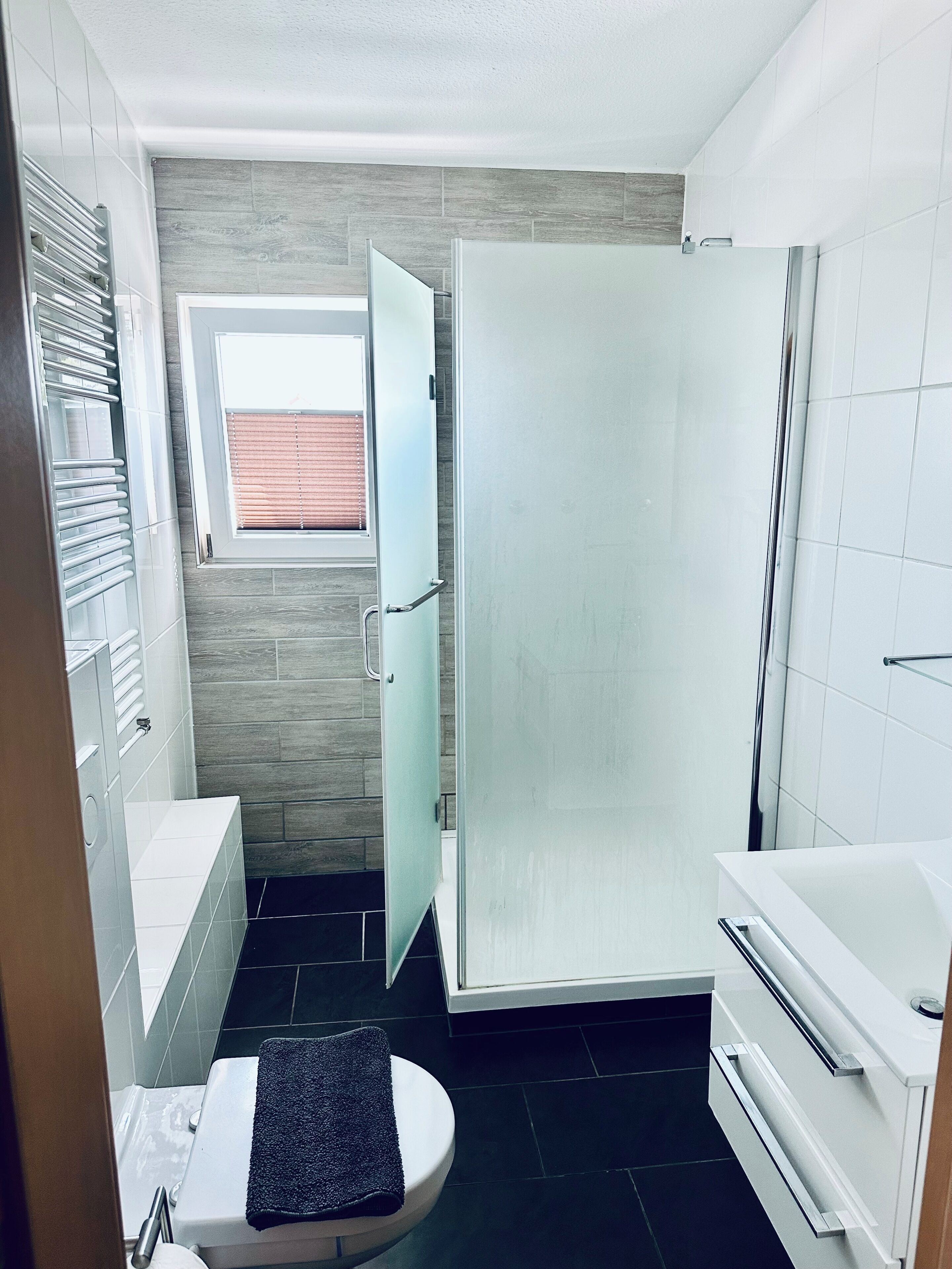 Un bagno con vasca, WC, doccia e una finestra con persiane.