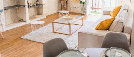 Una sala moderna con comedor, un televisor de pantalla plana montado en una pared texturizada y vista al exterior a través de una puerta de vidrio.