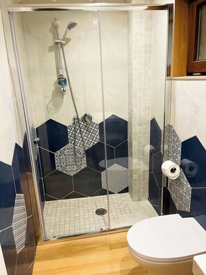 Eine Dusche mit Glastür, eine Toilette und ein Waschbecken.