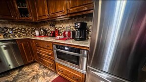 A kitchen with wooden cabinets, a stainless steel refrigerator, a built-in oven, and a coffee maker. - River Retreat (Valliant)