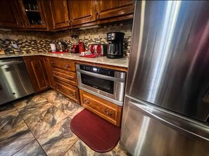 A kitchen with wooden cabinets, a stainless steel refrigerator, a built-in oven, and a coffee maker. - River Retreat (Valliant)