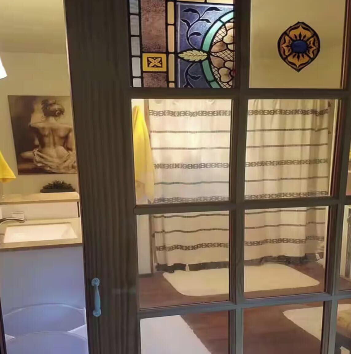Un bagno con tenda della doccia, porta asciugamani e un'opera d'arte incorniciata al muro.