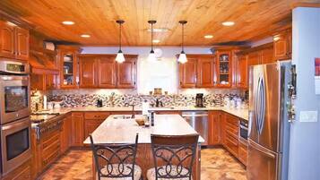 A kitchen with wooden cabinets, a central island, stainless steel appliances, and pendant lighting.