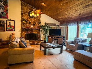 A cozy living room with a stone fireplace, a flat-screen TV, and comfortable seating. - River Retreat (Valliant)
