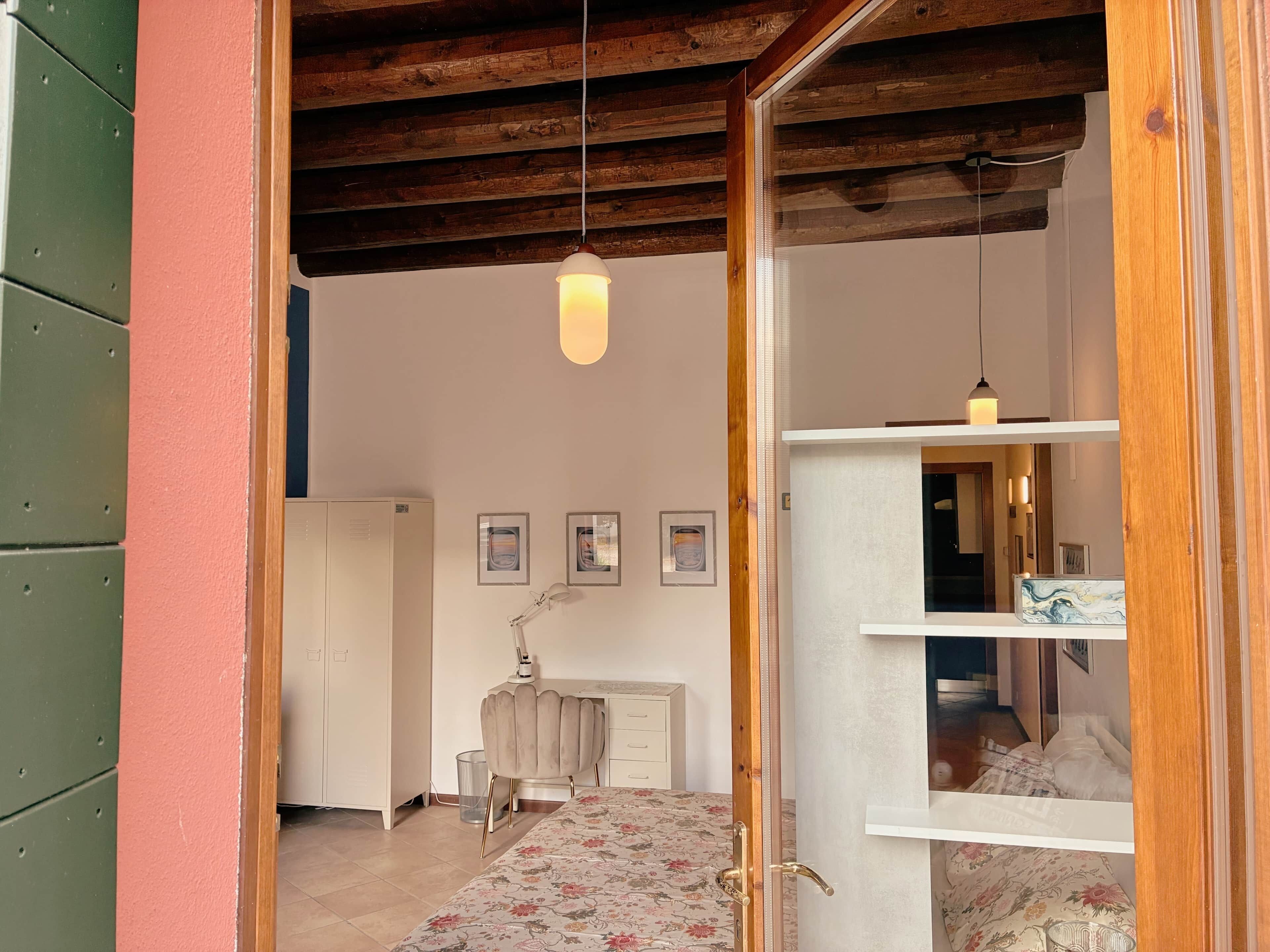 A room with a bed, a desk, a chair, a radiator, and a hanging light fixture.