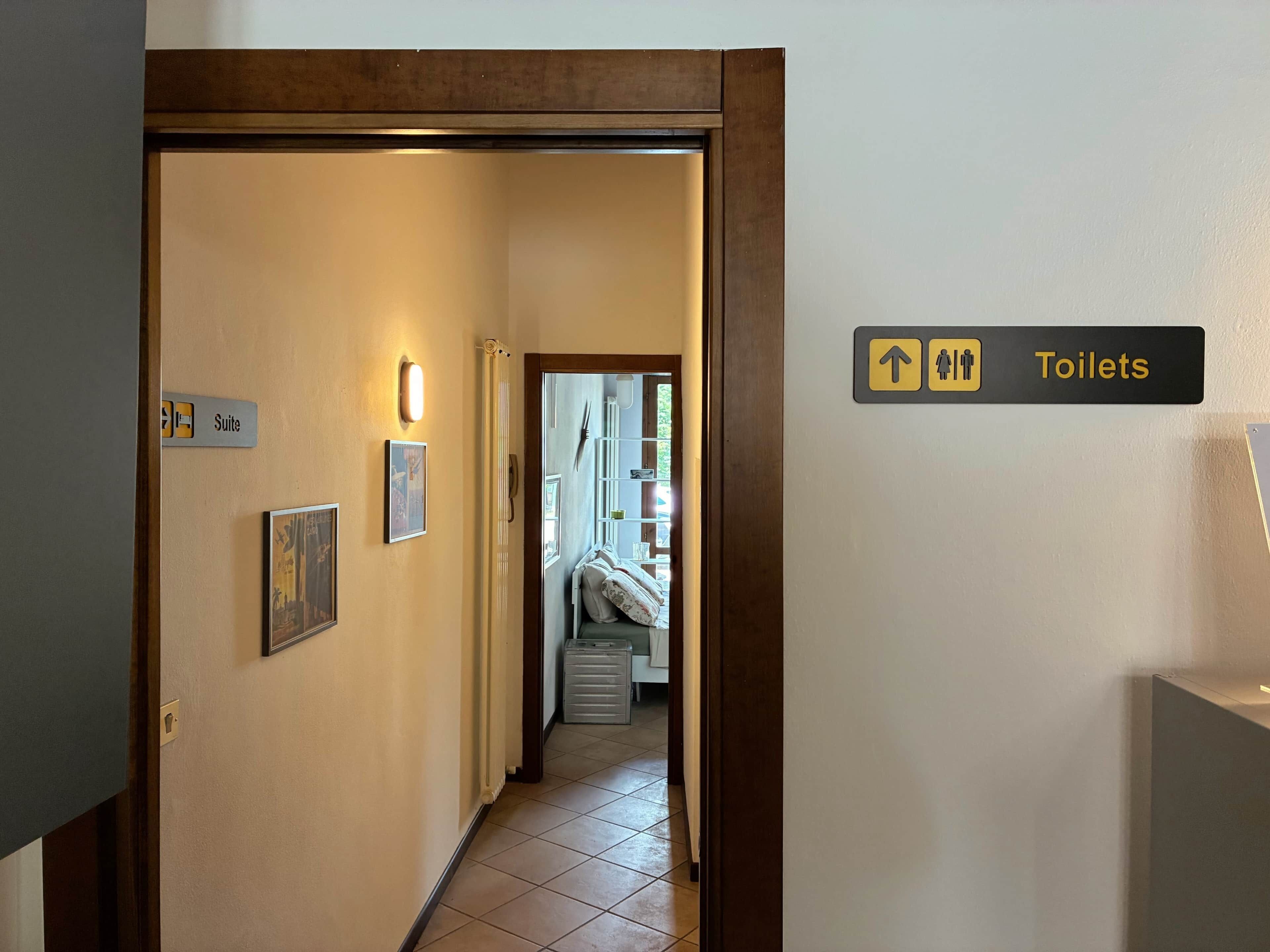 A hotel hallway with a sign indicating the direction to the toilets.