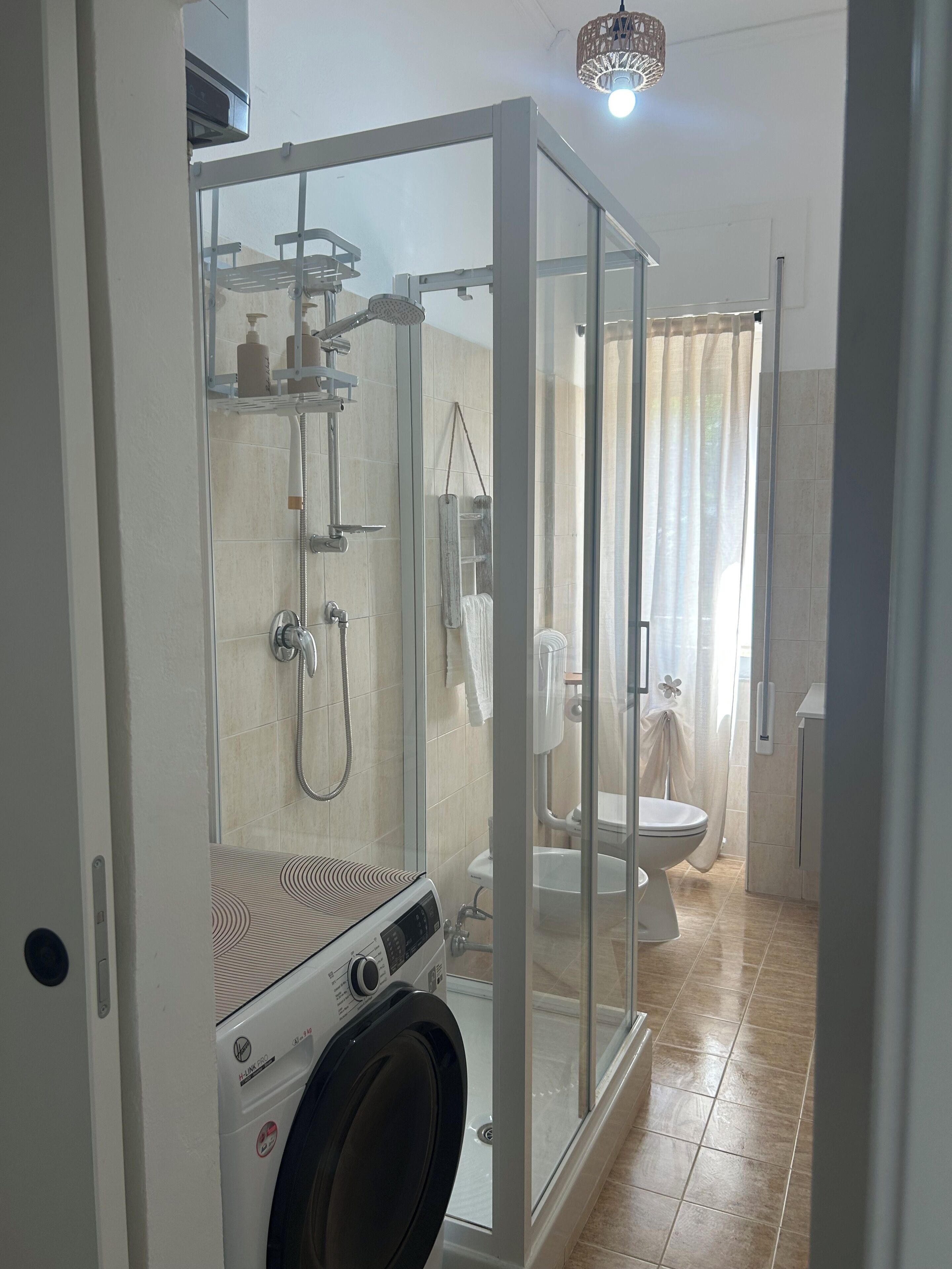 Une salle de bain moderne dotée d’une douche à parois de verre, de toilettes et d’un lave-linge.