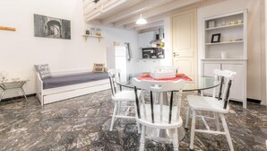 Una cocina moderna con armarios blancos, una mesa de comedor de cristal y sillas blancas.