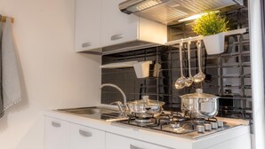 Una cocina moderna con estufa a gas, electrodomésticos de acero inoxidable y un salpicadero de azulejos negros.
