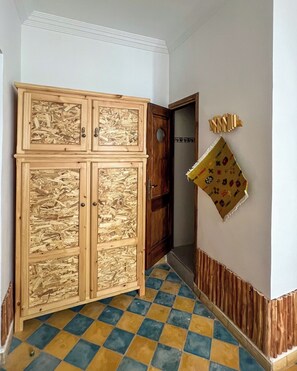 Un pasillo con un gran armario de madera con múltiples puertas, piso de cuadros y un adorno en la pared.