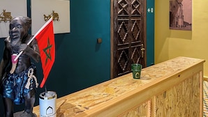 Mostrador de recepción con un cartel que dice 'WELCOME', una bandera marroquí y una estatua.