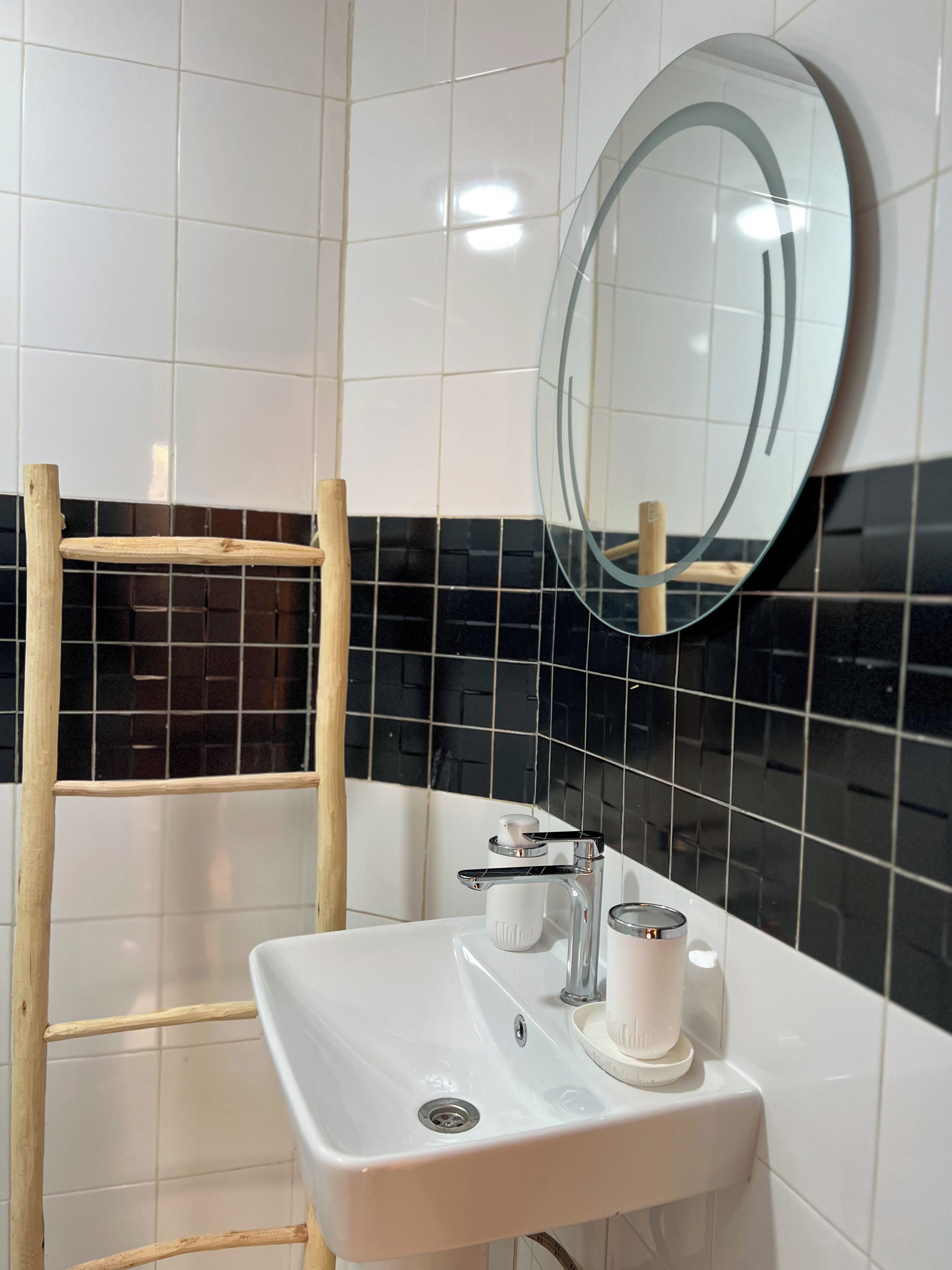 A bathroom with a white sink, a mirror, and a wooden ladder.