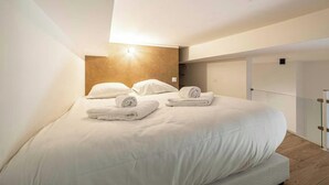 Une chambre d’hôtel avec un grand lit, deux oreillers et deux serviettes enroulées.