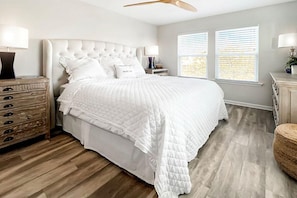 A bedroom with a large bed, wooden floor, and a ceiling fan. - Front and Sea (Port St. Joe)