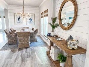 A dining area with wicker furniture, a wooden console table, and a large mirror. - Front and Sea (Port St. Joe)