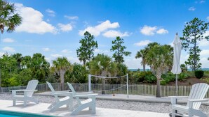 A pool area with white lounge chairs and a white fence. - Arlanymor (Port St. Joe)