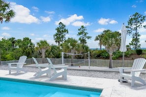 A pool area with white lounge chairs and a white fence. - Arlanymor (Port St. Joe)
