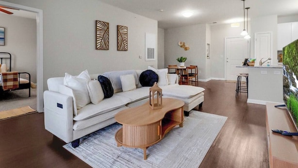 A modern living room with a sofa, coffee table, and a kitchen area with a bar. - 2BR/2BA Luxury | Walkable + Parking | PET Friendly (Charlotte)