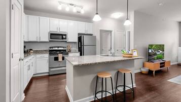 A modern kitchen with white cabinets, stainless steel appliances, and a central island with stools.