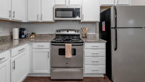 A kitchen with white cabinets, a stainless steel stove, a microwave, and a refrigerator. - 2BR/2BA Luxury | Walkable + Parking | PET Friendly (Charlotte)